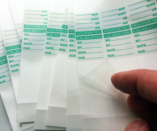 An image of several pages of quality control labels that have self-laminating tails.