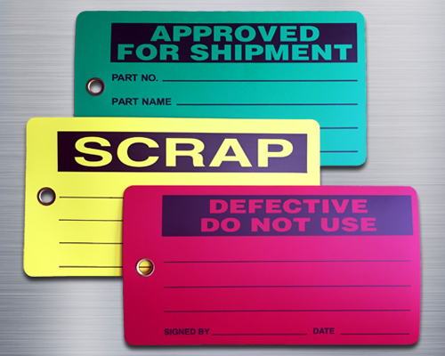 An image of three production status tags: "Approved for Shipment" in black on green, "Scrap" in black on yellow and "Defective, Do Not Use" in black on red. All three tags are rectangular with rounded corners and metal eyelets.