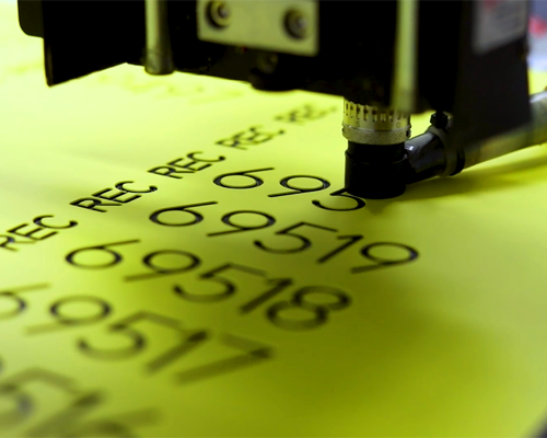 A Yellow plastic sheet being engraved with numbers.