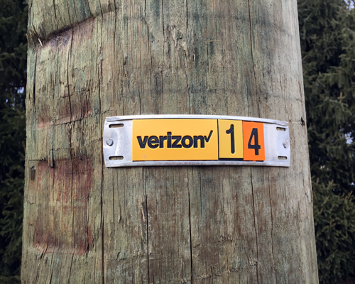 A utility pole marker showing a utility name on a telephone pole