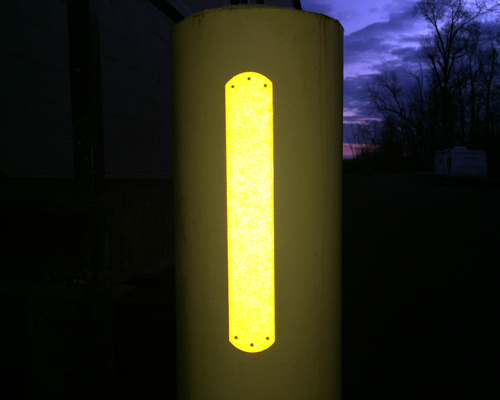 A reflective visibility strip on a concrete bollard.