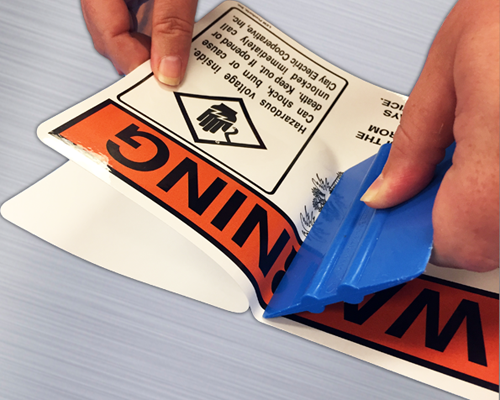 A pressure sensitive label being applied to a surface with a squeegee.