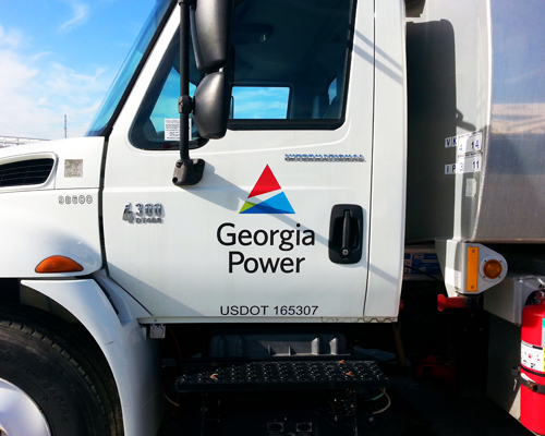 A utility truck displays a reflective fleet decal panel graphic on the cab door including the DOT fleet vehicle semi truck number.
