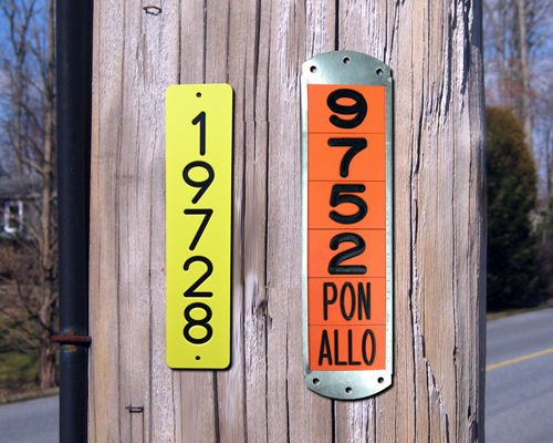 A sequentially engraved plastic pole tag and a standard engraved pole tag on a telephone pole.